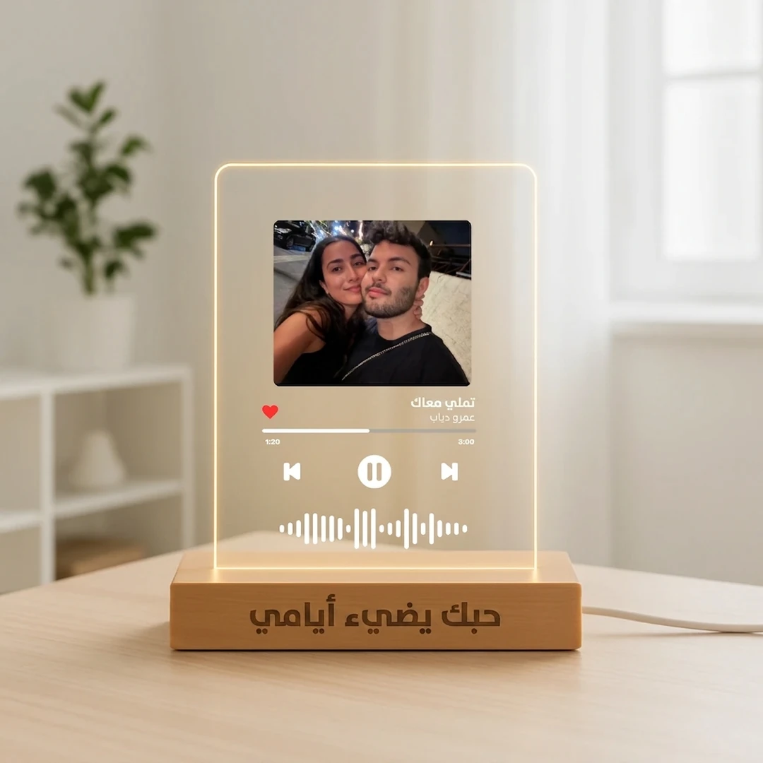 Personalized Arabic MusicGlass night light on a wooden table, showing a couple photo, the Arabic song تملي معاك and an Arabic engraving on the wooden base
